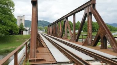 Çelikten yapılmış eski tren köprüsü perspektifle yeşil dağlara ve nehre bakıyor.