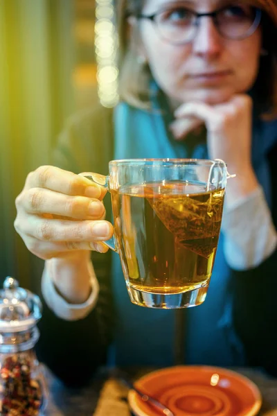 Traurige Frau trinkt Darjeeling-Tee in gemütlichem Café — Stockfoto