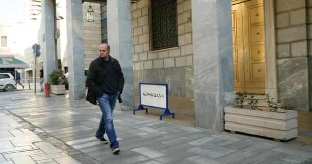 アテネ ギリシャ Circa 2016 人々はアテネ中央部のアルファ銀行支店の近くを歩いています アルファ銀行は総資産で4番目に大きいギリシャの銀行ですが 2月2017の時点で24億5千万ユーロの時価総額で最大の銀行です — ストック動画