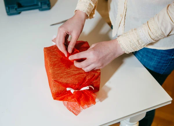 Vrouw wrap geschenk voor vakantie rode zijden papier snijden — Stockfoto