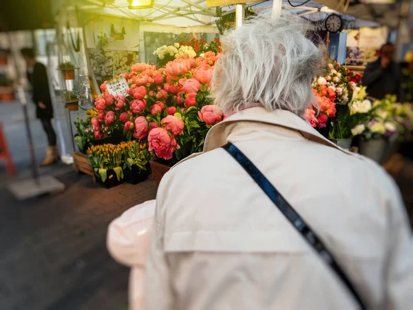 Starší žena nákupu květin v květinářství — Stock fotografie