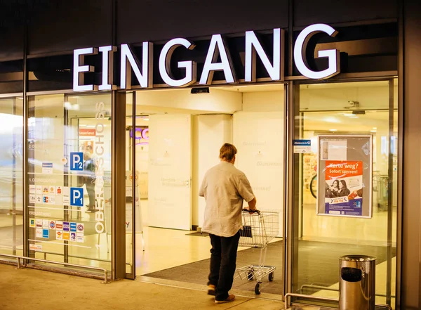 Homem com carrinho de compras penetrando loja Edeka sob Eingang entra — Fotografia de Stock