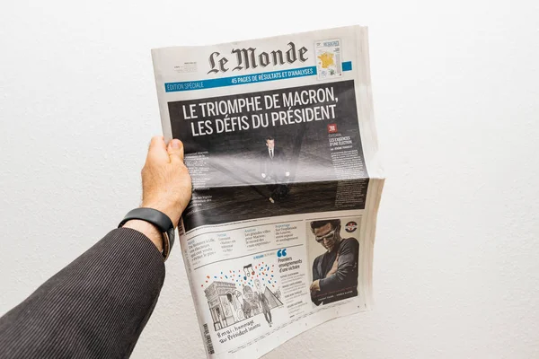 Hombre sosteniendo el periódico Le Monde con Emmanuel Macron en la primera pag — Foto de Stock