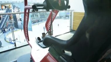 BUCHAREST, ROMANIA - CIRCA 2016: Üç monitörlü ve 3 boyutlu hareketli özel donanımlı bilgisayar platformunda aksiyon yarışı oyunu oynayan üç monitöre bakan araba simülatörü