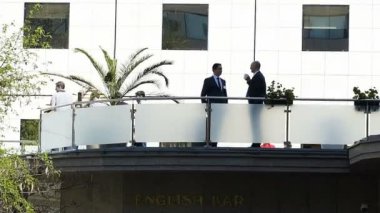 Modern binanın balkonunda konuşan iş adamları