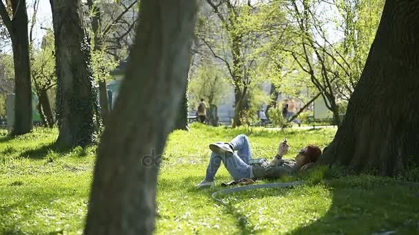 Mujer usando teléfono bajo el árbol — Vídeos de Stock