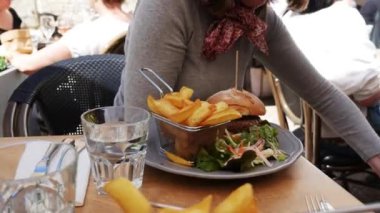 plaka masada büyük hamburger ile gri elbise giyen kadın Close-Up
