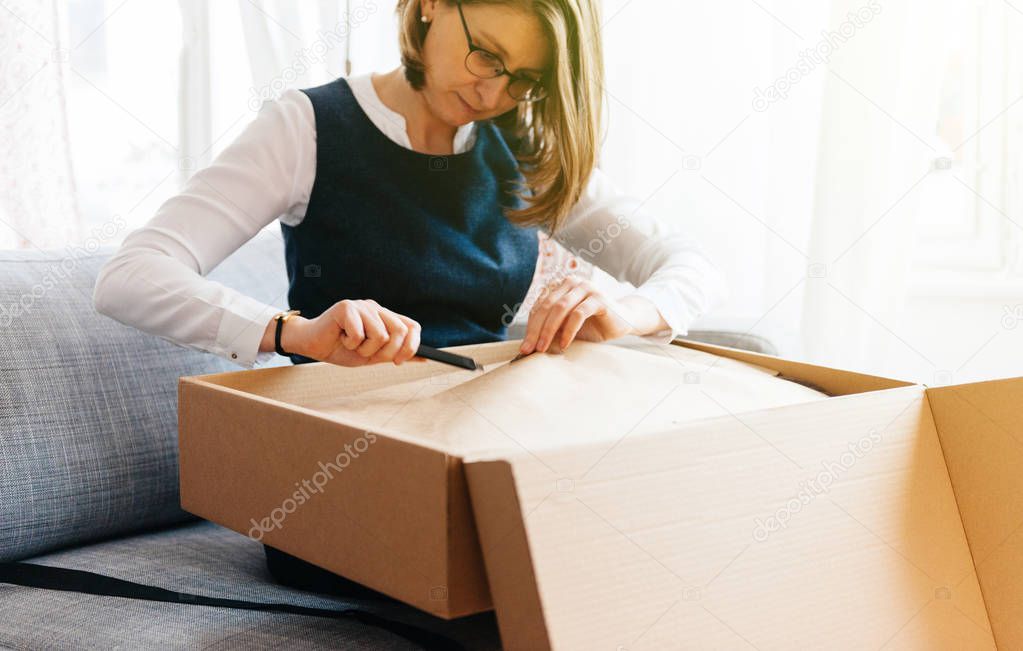 Woman unpacks unboxing new parcel containing fashion clothes 