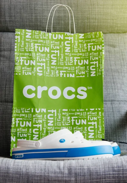 Crocs zuecos zapatos bolsa de compras sobre fondo gris — Foto de Stock