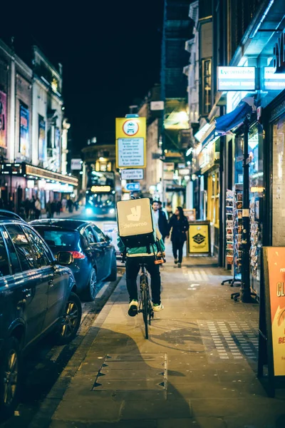 Noční rozvoz jídel od Deliveroo biker v rušném městě — Stock fotografie