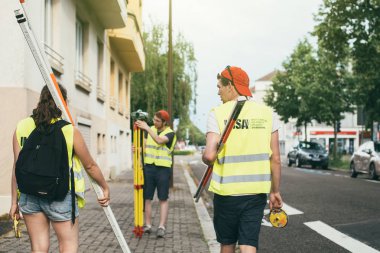 Öğrencilerle surveyor mühendis teodolit ile şehir üzerinde çalışıyor