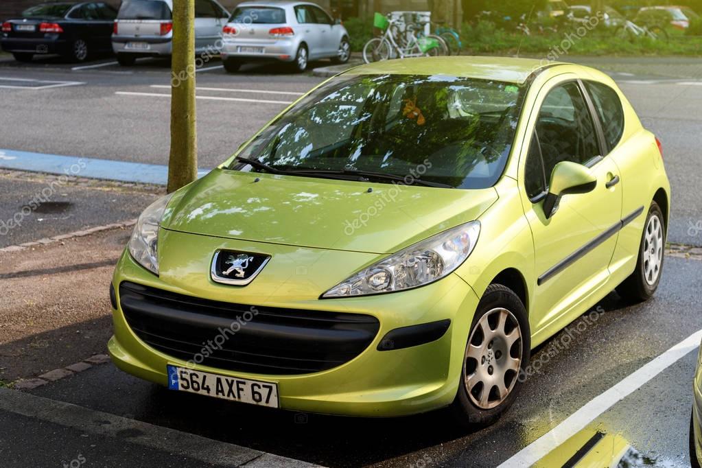 STRASBOURG, FRANCE - MAY 30, 2017: Lion logotype of in front of a green Peugeot 206 city car parked on the street. Peugeot is one of the bigest car manufacturer in the world
