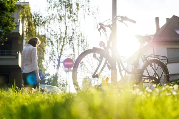 Mujer caminando cerca de la bicicleta en el área urbana — Foto de Stock