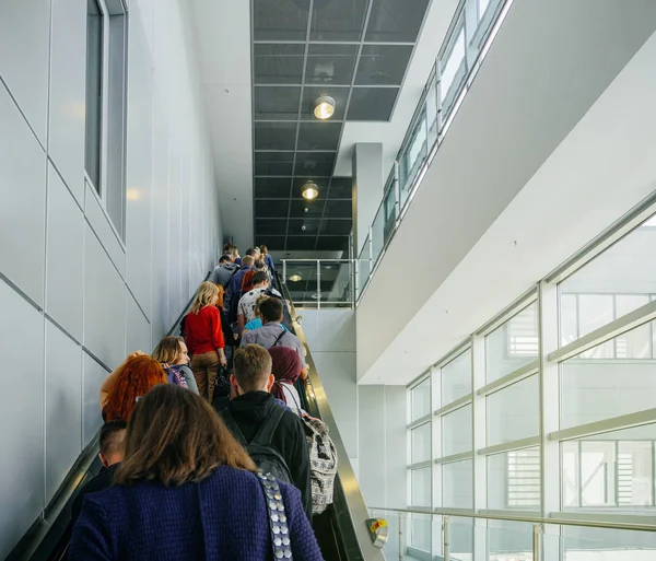 Pasajeros que viajan en la escalera mecánica en la moderna terminal del aeropuerto — Foto de Stock