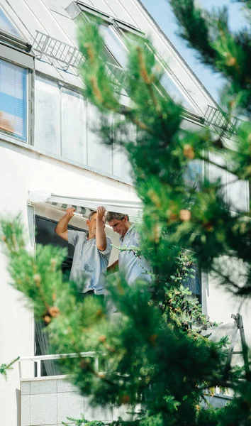 Equipe instalando toldo proteção solar na janela balckony — Fotografia de Stock