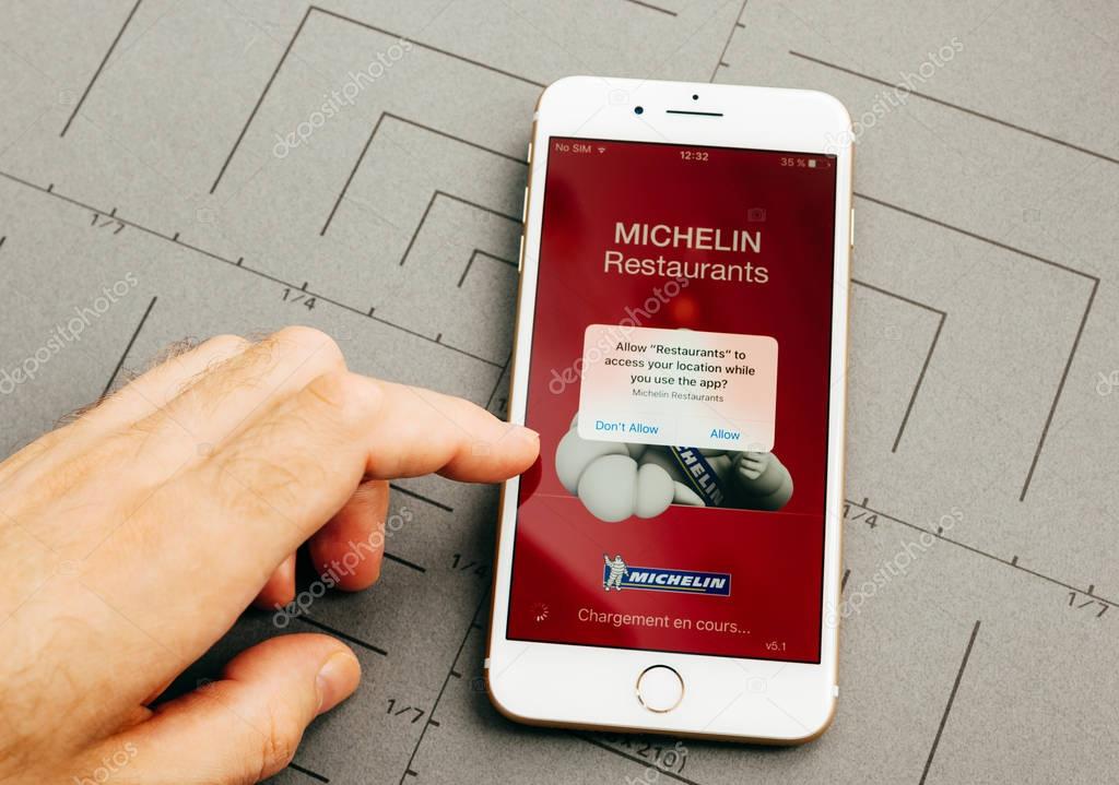 PARIS, FRANCE - SEP 26, 2016: Male hand holding New Apple iPhone 7 Plus after unboxing and testing by installing the app application software Michelin restaurants app
