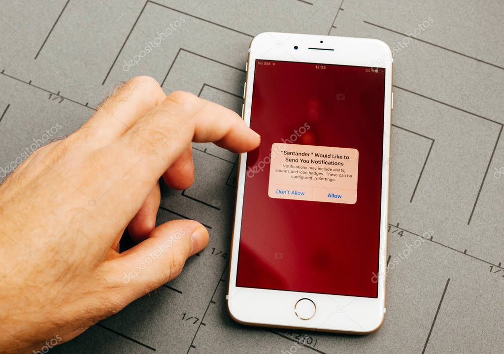 PARIS, FRANCE - SEP 26, 2016: Male hand holding New Apple iPhone 7 Plus after unboxing and testing by installing the app application software online banking Santander bank