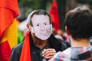 Protesto olarak Emmanuel macron maskesi giyen adam 