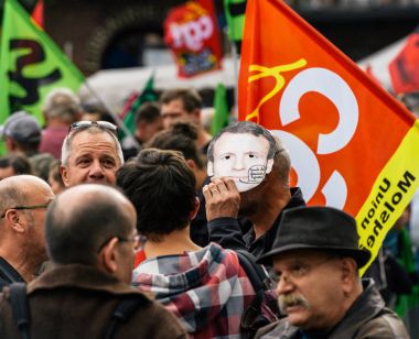 Protesto olarak Emmanuel macron maskesi giyen adam 