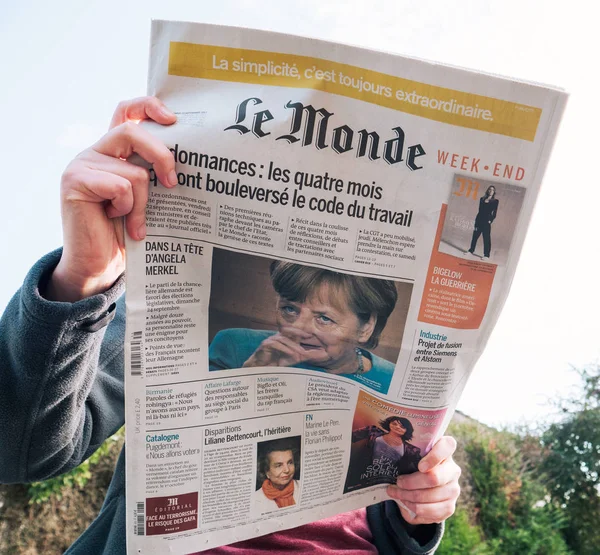 Женщина, читающая французскую прессу Le Monde, Ангела Меркель — стоковое фото