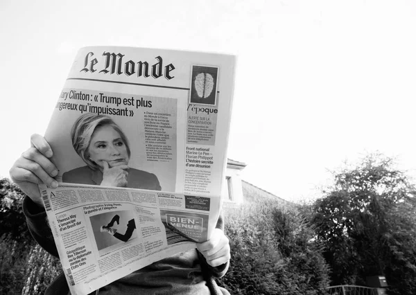 Снизу женщина читает свежую газету Le Monde с портретом Хиллари Клинтон — стоковое фото