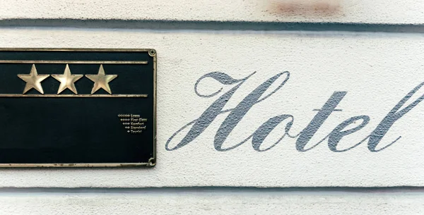 Красивая каллиграфическая табличка HOTEL рядом с фасадом из трех звезд — стоковое фото