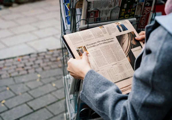 Женщина покупает газету FT Weekend — стоковое фото