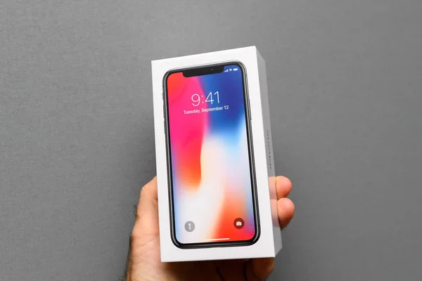 Человек держит Apple iPhone X10 на сером фоне — стоковое фото