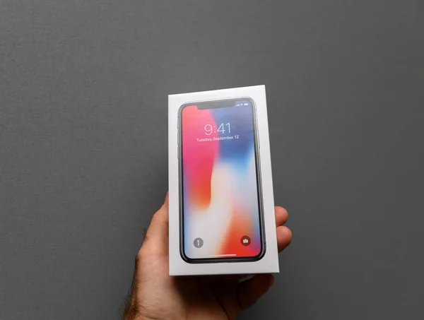 Чоловік тримає Apple iphone X10 проти сірий фон — стокове фото