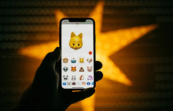 Мужчина держит новый смартфон Apple iPhone X на фоне звезды с анимом — стоковое фото