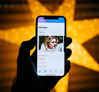 Paris, Fransa - 10 Kasım 2017: Louane müzik sanatçı Gözat Apple müzik featuring sarı yıldız bokeh arka plan ile yeni Apple iphone X 10 ekran tutan adam 