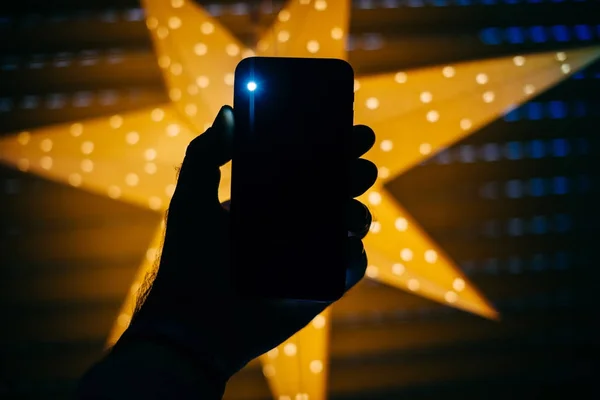Человек Держащий Руках Новый Телефон Фоне Желтой Звезды Бокэ Подсветкой — стоковое фото