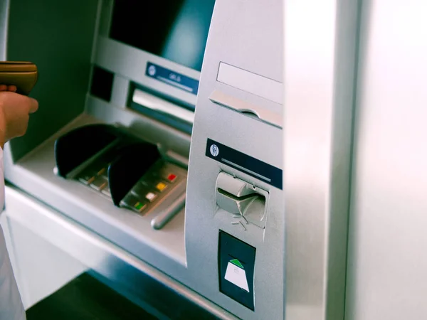 Woman using ATM Automatic Teller Machine cash machine to enter the security PIN and retrieve withdrawal withdrawal money