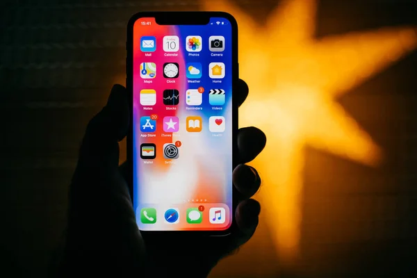 Νέο iphone της Apple ενάντια σε μπλε defocused αστέρι που χαρακτηρίζει το σπίτι εφαρμογές — Φωτογραφία Αρχείου