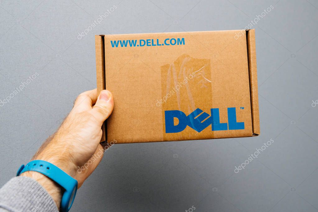 PARIS, FRANCE - NOV 6, 2017: Man holding against gray background cardboard box with DELL computer logo spare part inside for his IT department