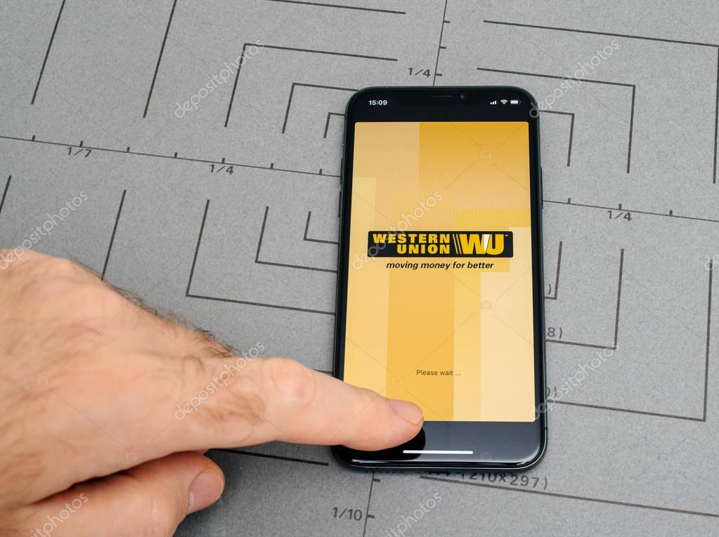 PARIS, FRANCE - NOV 9, 2017: Male hand touch selecting New Apple iPhone x 10 smartphone after unboxing and testing by installing the Western Union money transfer app application software