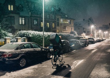 Strasbourg, Fransa - 3 Aralık 2017: Sinema Deliveroo teslim Bisiklet Fransız City park etmiş arabalar ile fast food teslim için semtte bir soğuk kış karlı gecede zamanında Bisiklete binme