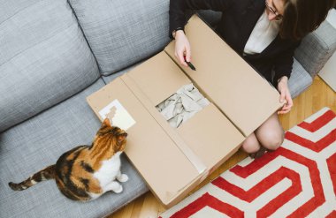 Kadın unboxing karton yardım ediliyor onun cat - in üstünden online alışveriş kavramı görüntülemek