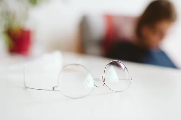 Gafas de gafas en la mesa con silueta de mujer en la espalda —  Fotos de Stock