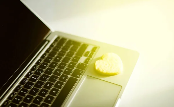 Heart shaped cookie snack on modern aluminium professional laptop keyboard