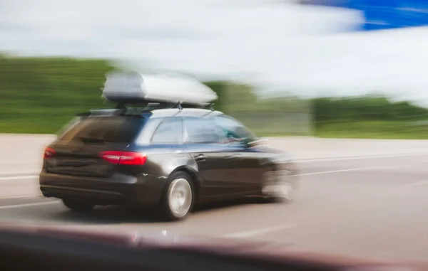 Cargo carrier on top of wagon car driving fast on highway