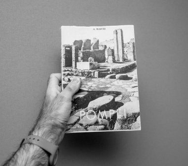 Lyon, Fransa - 30 Eylül 2017: gri bir arka plana dayanır Pompei Amadeo Maiuri tarafından başlıklı vintage eski kitap tutan adam