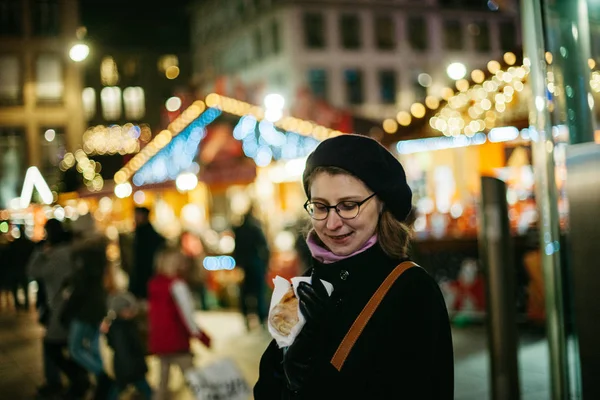 Kvinna Som Äter Traditionell Julmat Med Oskärpa Suddig Julmarknad Bakgrunden — Stockfoto