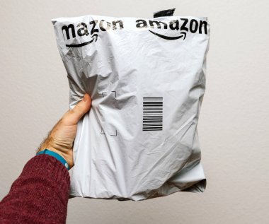 Paris, Fransa - 23 Ocak 2018: beyaz arka plan üzerinde Amazon paket giysi ya da içeren plastik parsel teslimini tutan adam