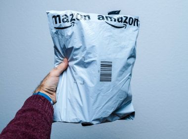 Paris, Fransa - 23 Ocak 2018: beyaz arka plan üzerinde Amazon paketi plastik parsel teslimini tutan adam