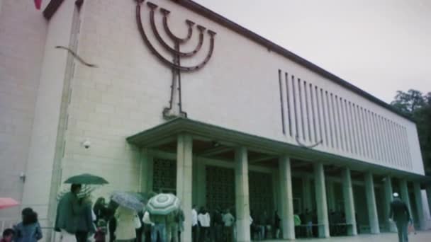 Personas esperando en cola para entrar en la sinagoga en un día lluvioso — Vídeo de stock