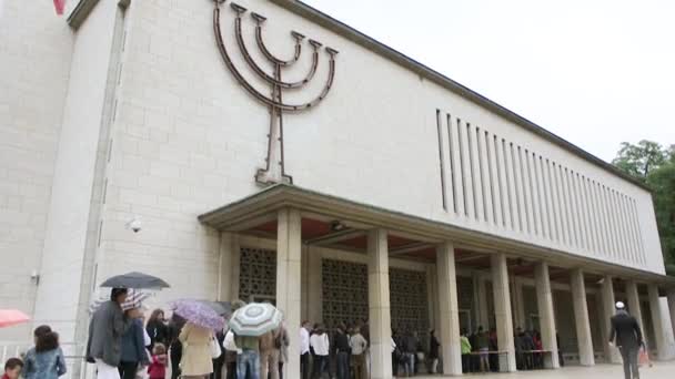 Les gens qui attendent dans la file d'attente pour entrer dans la synagogue un jour de pluie — Video