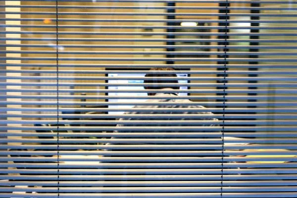 Silueta de hombre de negocios trabajando hasta tarde visto a través de ventanas —  Fotos de Stock