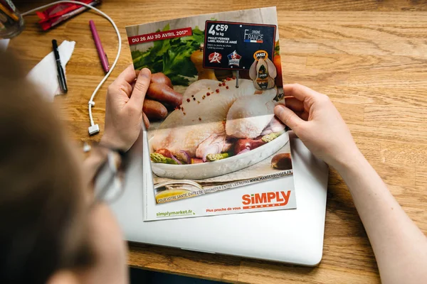 Mujer leyendo Simply Auchan folleto periódico boletín de noticias — Foto de Stock