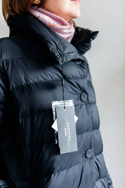 マックスマーラ ダウン ジャケットを見て女性が新しい服の値札を購入します。 — ストック写真